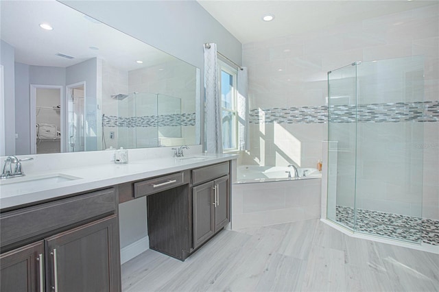 bathroom with tile flooring, independent shower and bath, dual sinks, and vanity with extensive cabinet space