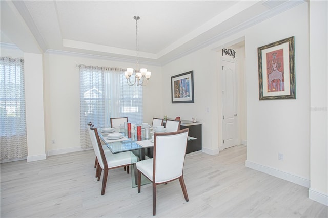 dining area with a raised ceiling, an inviting chandelier, light hardwood / wood-style floors, and a healthy amount of sunlight