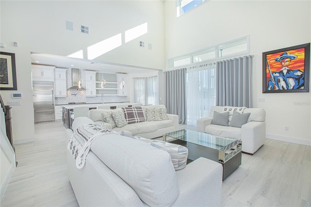 living room featuring plenty of natural light, a towering ceiling, and light wood-type flooring