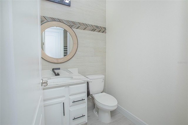 bathroom featuring toilet, vanity, and tile walls