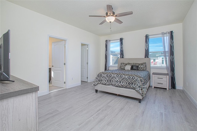 bedroom with connected bathroom, a textured ceiling, ceiling fan, and light hardwood / wood-style flooring