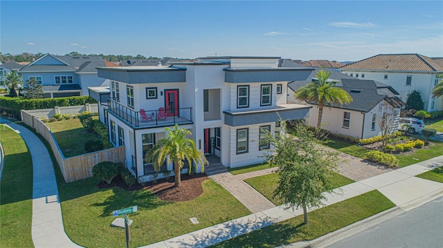 view of front of home with a balcony and a front yard