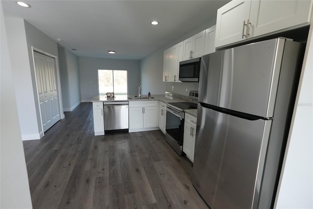 kitchen featuring white cabinetry, sink, dark hardwood / wood-style flooring, kitchen peninsula, and appliances with stainless steel finishes