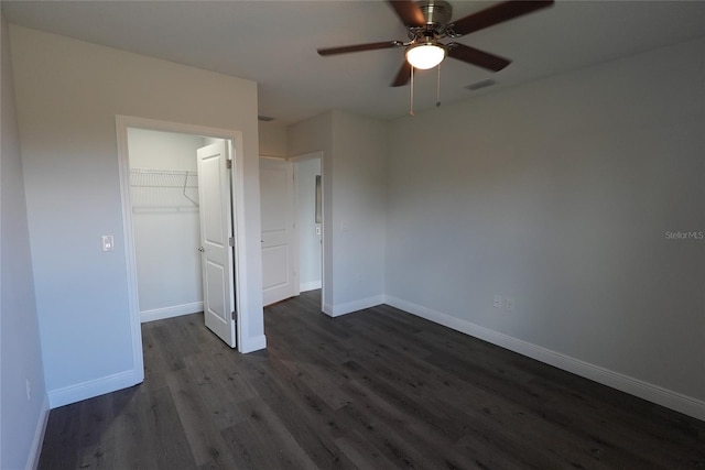 unfurnished bedroom featuring dark hardwood / wood-style flooring, ceiling fan, a closet, and a spacious closet