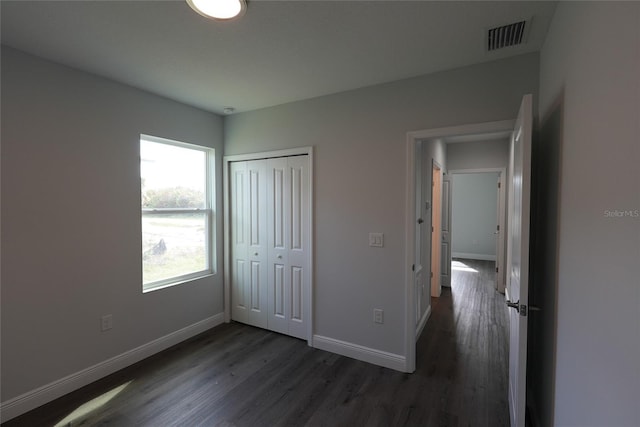 unfurnished bedroom with a closet and dark hardwood / wood-style floors