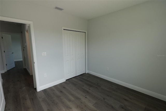 unfurnished bedroom featuring a closet and dark hardwood / wood-style floors