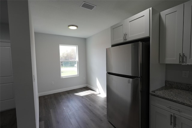 kitchen featuring white cabinets, stainless steel fridge, wood-type flooring, and light stone countertops