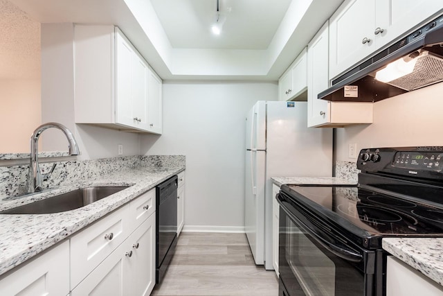 kitchen with light stone countertops, light hardwood / wood-style flooring, black appliances, white cabinets, and sink