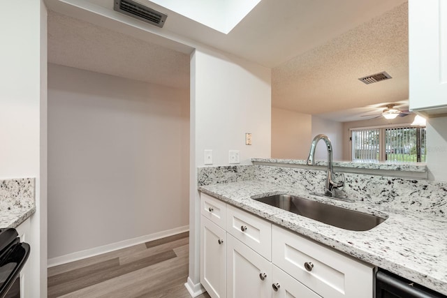 kitchen featuring white cabinets, light stone countertops, ceiling fan, and sink