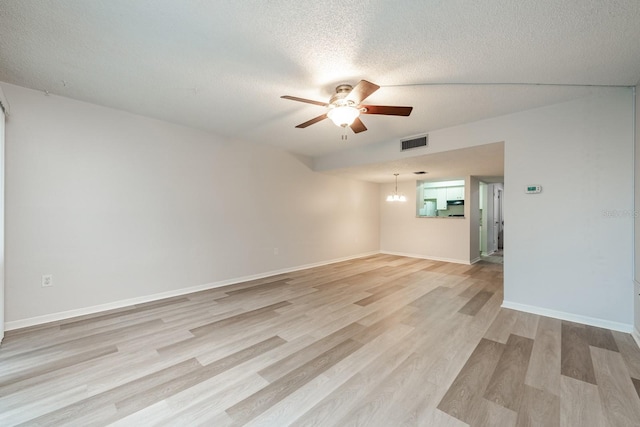 unfurnished room featuring a textured ceiling, ceiling fan with notable chandelier, and light hardwood / wood-style flooring