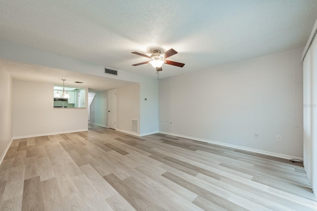 unfurnished room featuring a textured ceiling, ceiling fan with notable chandelier, and light hardwood / wood-style flooring