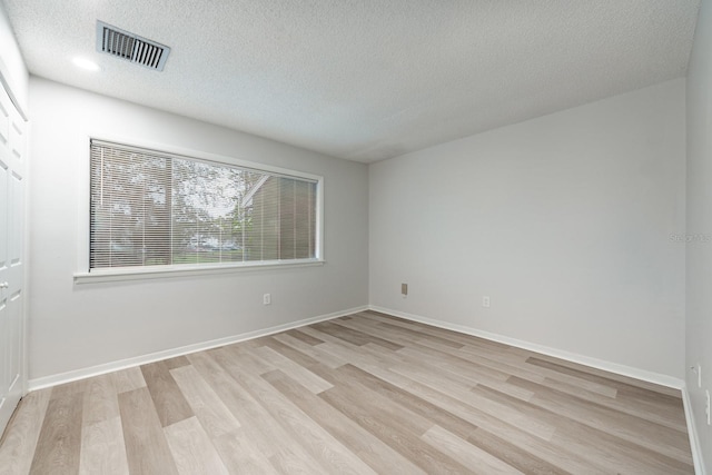 spare room featuring a textured ceiling and light hardwood / wood-style flooring