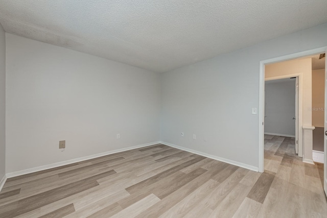 spare room featuring light hardwood / wood-style floors and a textured ceiling