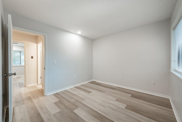 spare room featuring light hardwood / wood-style floors and a textured ceiling