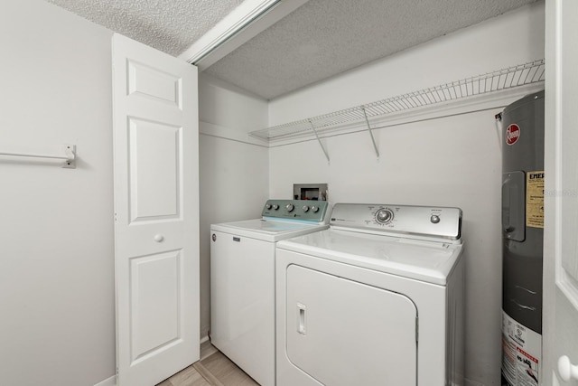 clothes washing area featuring a textured ceiling, washer and clothes dryer, electric water heater, and hookup for a washing machine