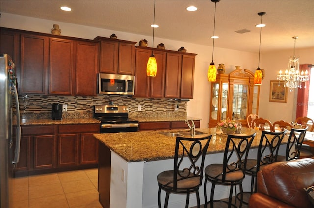 kitchen with stainless steel appliances, decorative light fixtures, a breakfast bar, and sink