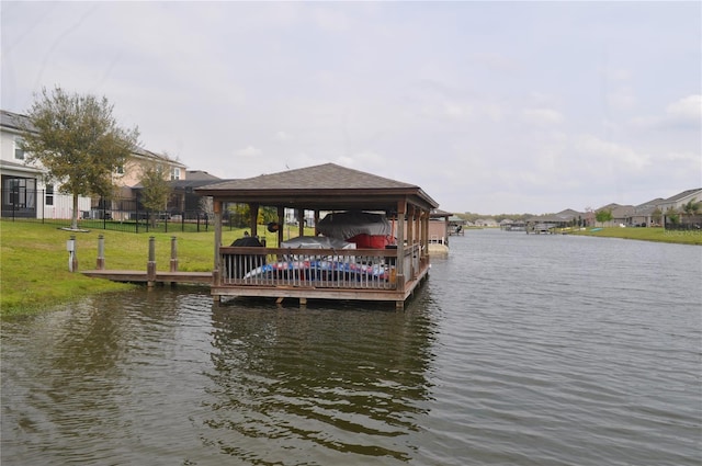 view of dock with a lawn and a water view