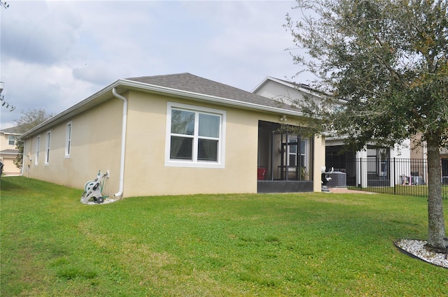 rear view of property with central AC, a lawn, and a sunroom