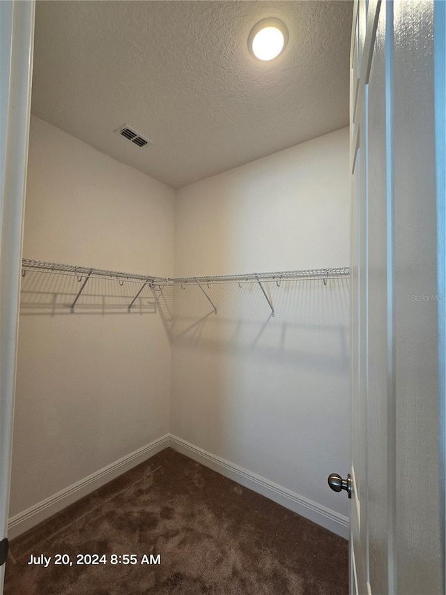 walk in closet featuring dark colored carpet