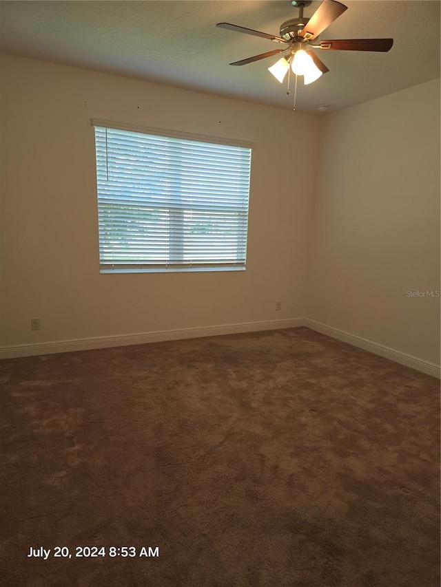 spare room with ceiling fan and dark colored carpet