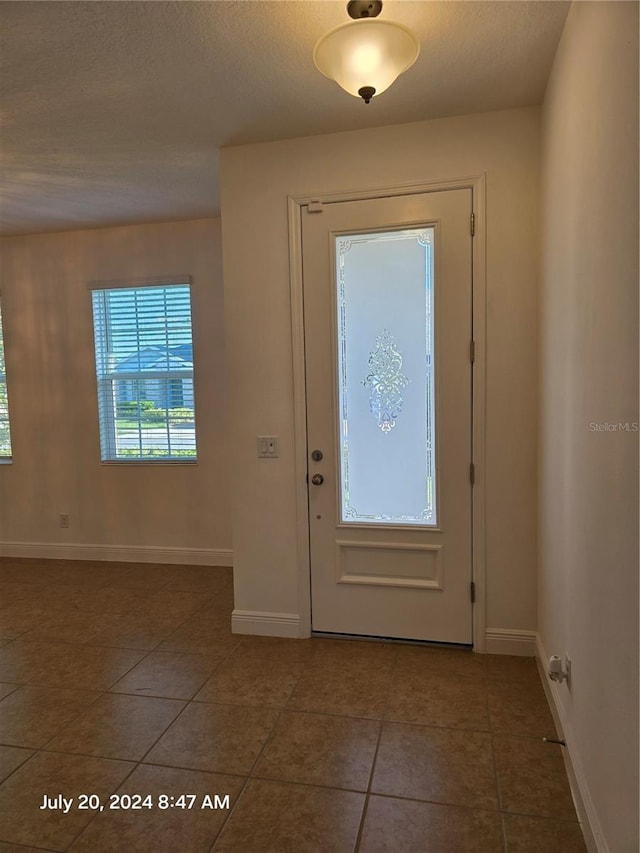 entryway featuring a textured ceiling and dark tile patterned floors