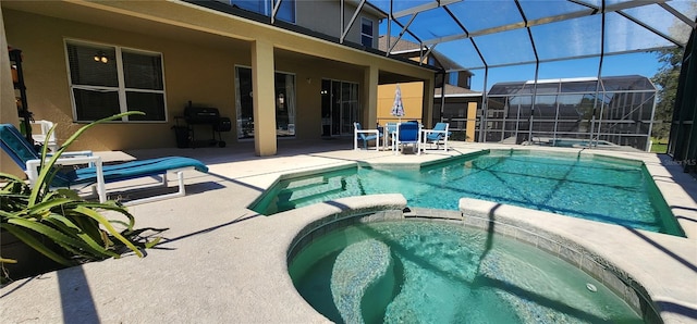 view of swimming pool featuring an in ground hot tub, glass enclosure, and a patio