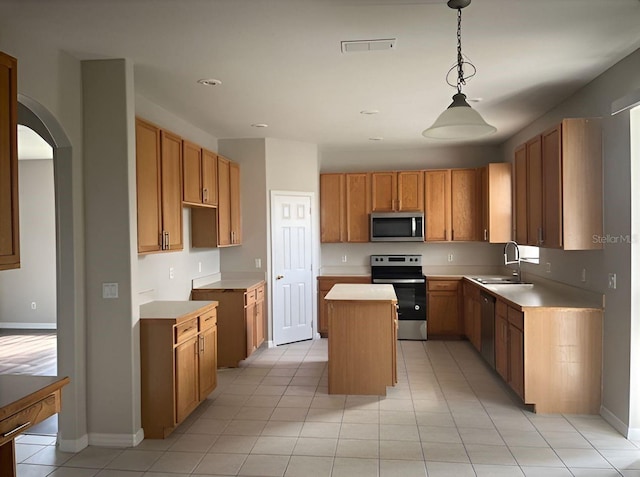 kitchen featuring appliances with stainless steel finishes, sink, light tile patterned floors, a kitchen island, and hanging light fixtures