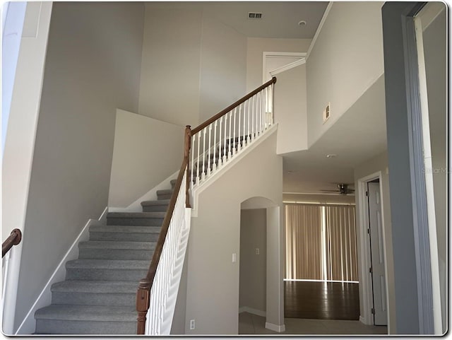 stairway featuring ceiling fan and a high ceiling