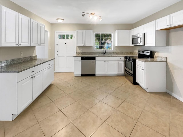 kitchen featuring appliances with stainless steel finishes, light tile patterned floors, white cabinetry, and sink