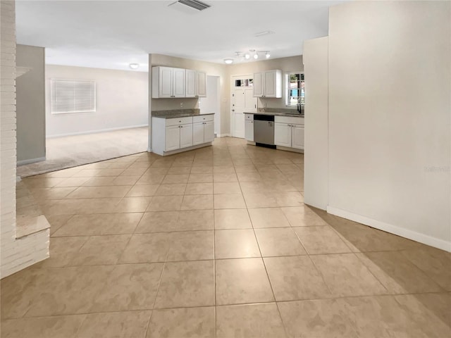 kitchen with white cabinets, dishwasher, light tile patterned flooring, and sink