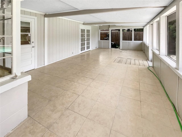 unfurnished sunroom with beamed ceiling