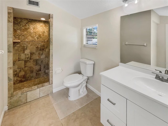 bathroom featuring tile patterned flooring, vanity, toilet, and a tile shower