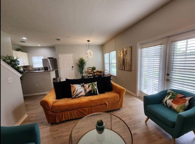 living room featuring a textured ceiling, a wealth of natural light, and light wood-type flooring