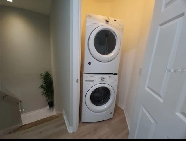 laundry area featuring stacked washer and dryer and light hardwood / wood-style floors