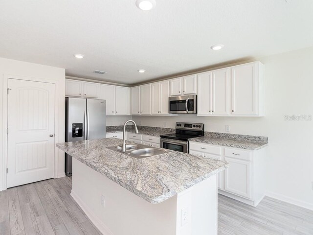 kitchen featuring white cabinets, stainless steel appliances, a center island with sink, and sink