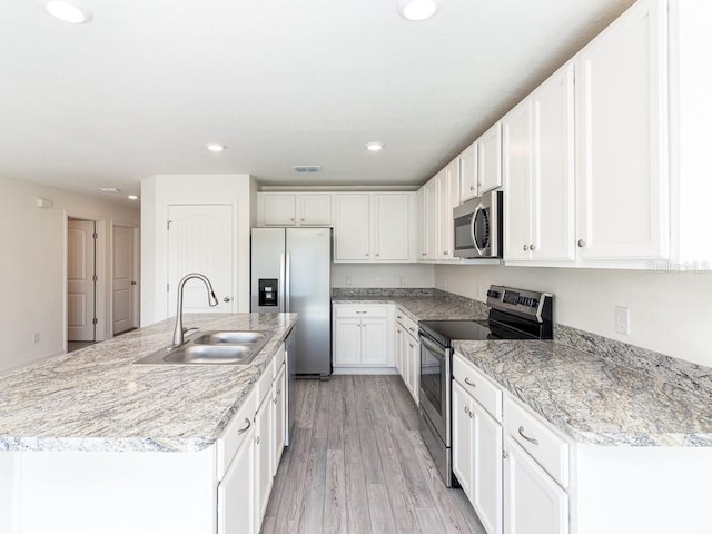 kitchen featuring white cabinetry, sink, stainless steel appliances, and a center island with sink