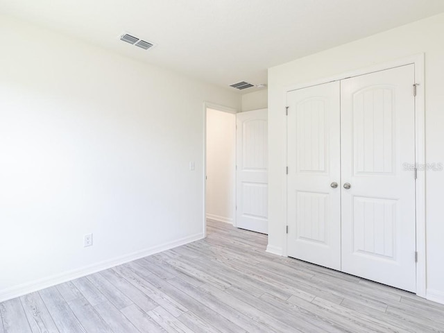 unfurnished bedroom with light wood-type flooring and a closet