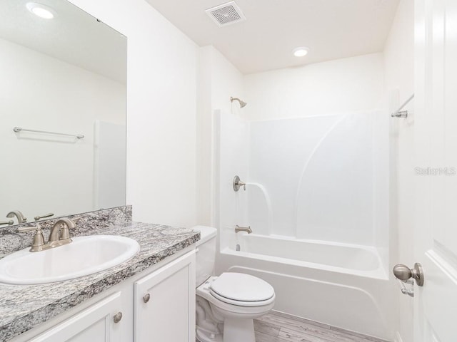 full bathroom featuring washtub / shower combination, hardwood / wood-style floors, vanity, and toilet