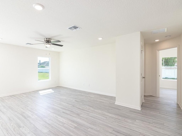 spare room with ceiling fan, light wood-type flooring, and a textured ceiling