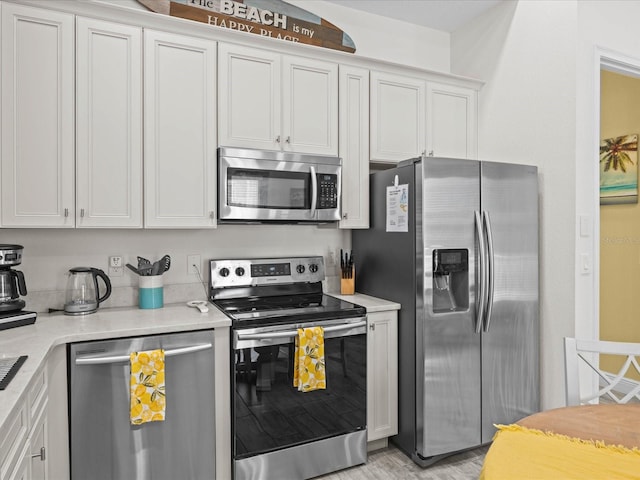 kitchen with stainless steel appliances, white cabinets, and light hardwood / wood-style flooring