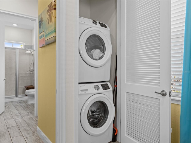 clothes washing area with light hardwood / wood-style floors and stacked washer and dryer