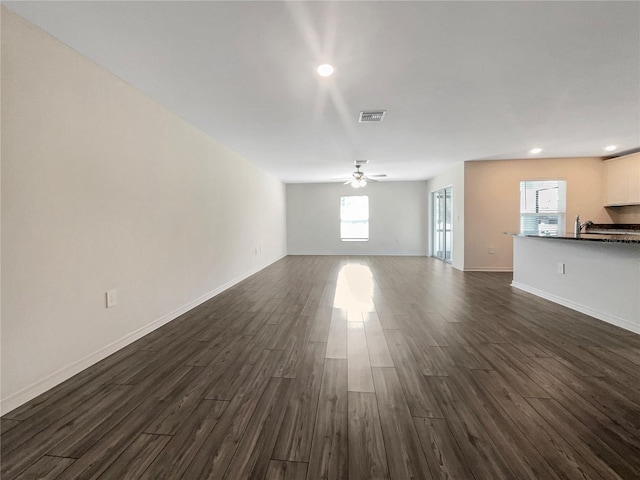 unfurnished living room with ceiling fan, dark wood-type flooring, and sink