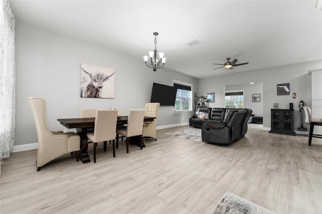 dining area featuring light hardwood / wood-style floors and ceiling fan with notable chandelier