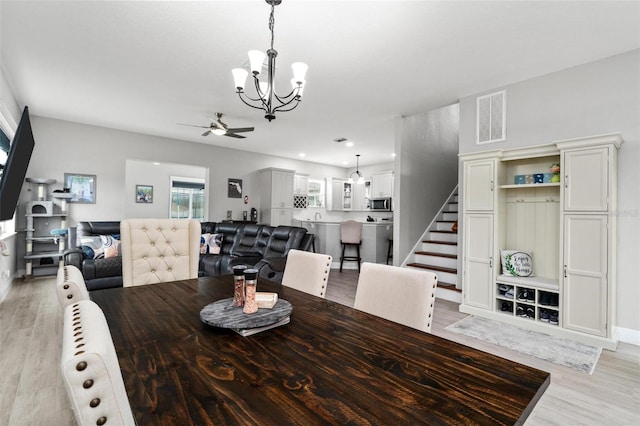 dining area featuring ceiling fan with notable chandelier and light hardwood / wood-style flooring