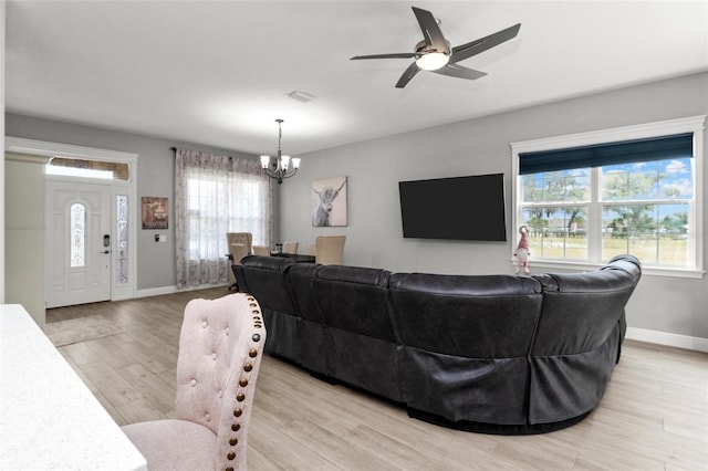 living room with a healthy amount of sunlight, ceiling fan with notable chandelier, and light wood-type flooring