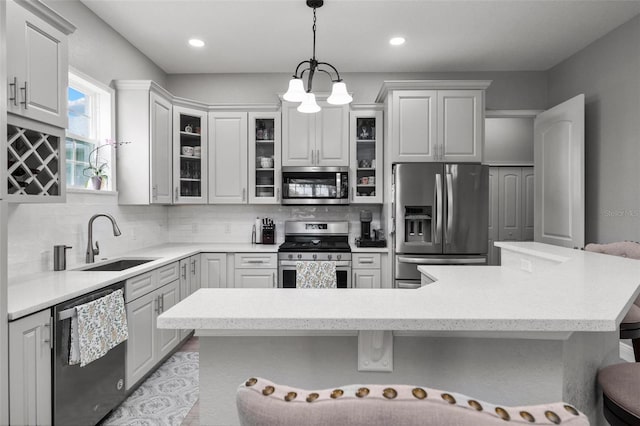 kitchen featuring a chandelier, pendant lighting, a kitchen breakfast bar, appliances with stainless steel finishes, and sink