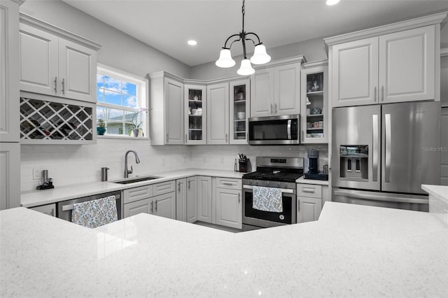 kitchen featuring backsplash, appliances with stainless steel finishes, a chandelier, and sink