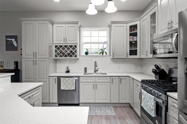 kitchen featuring appliances with stainless steel finishes, tasteful backsplash, light hardwood / wood-style floors, and sink