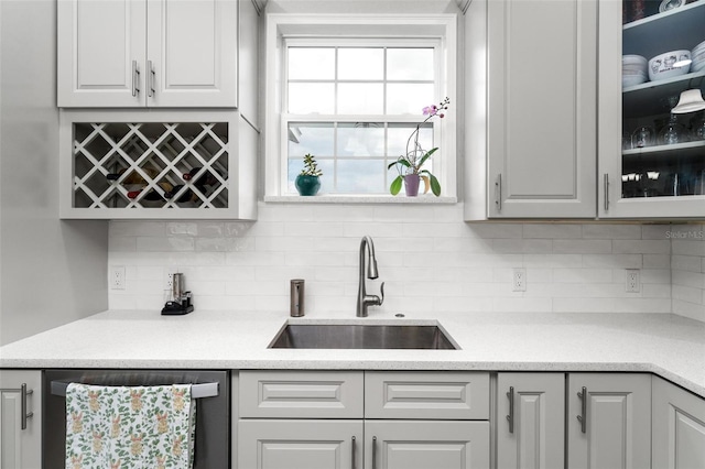 bar with backsplash, gray cabinets, dishwasher, and sink