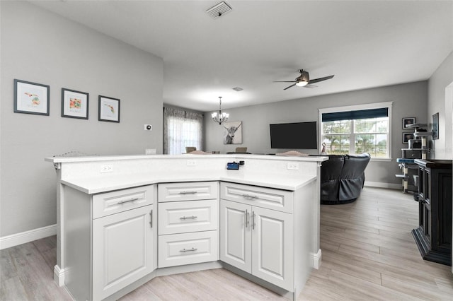 kitchen featuring white cabinetry, ceiling fan with notable chandelier, pendant lighting, and light wood-type flooring